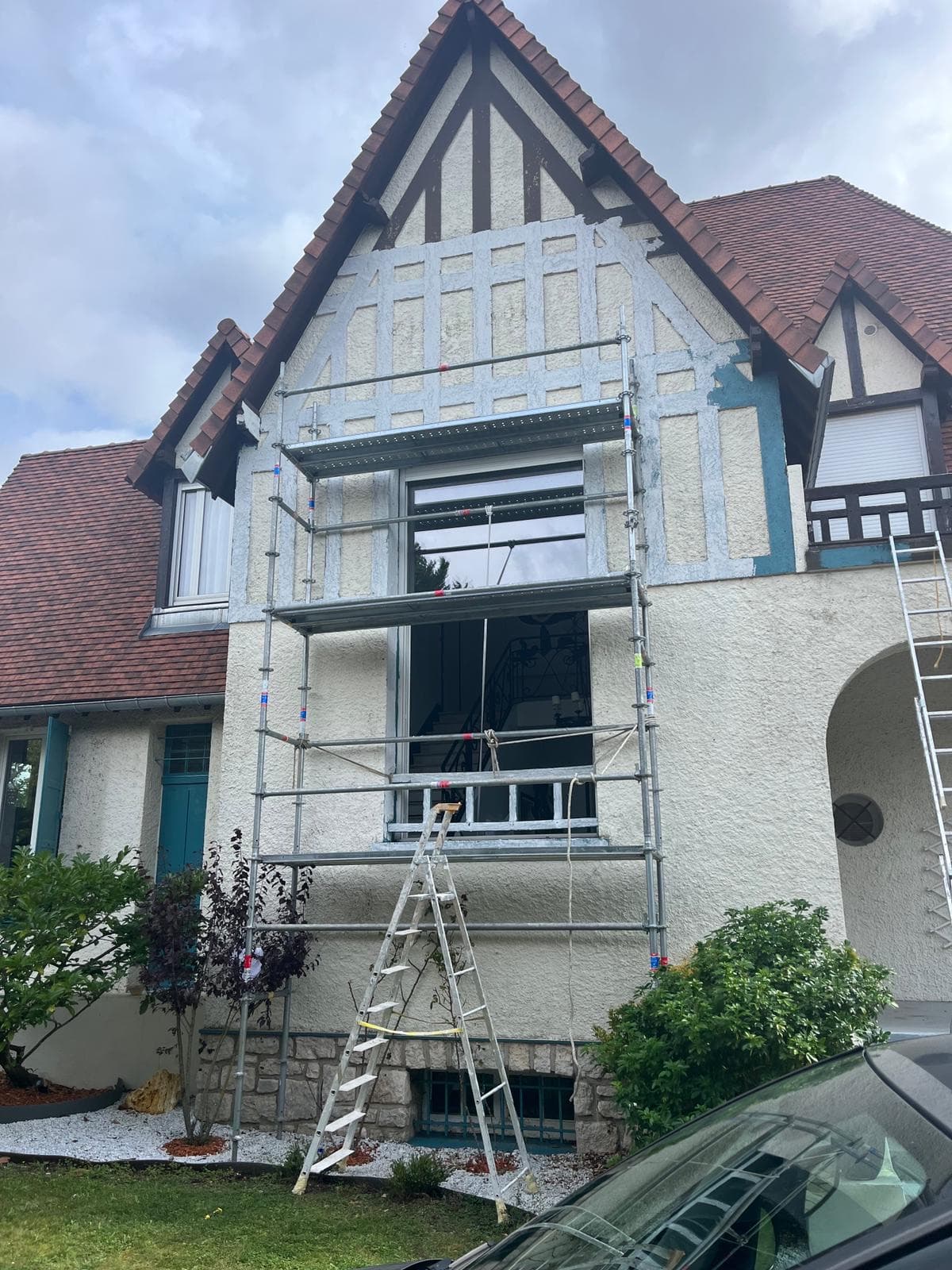 Façade de maison à colombages en cours de peinture, échafaudage en place