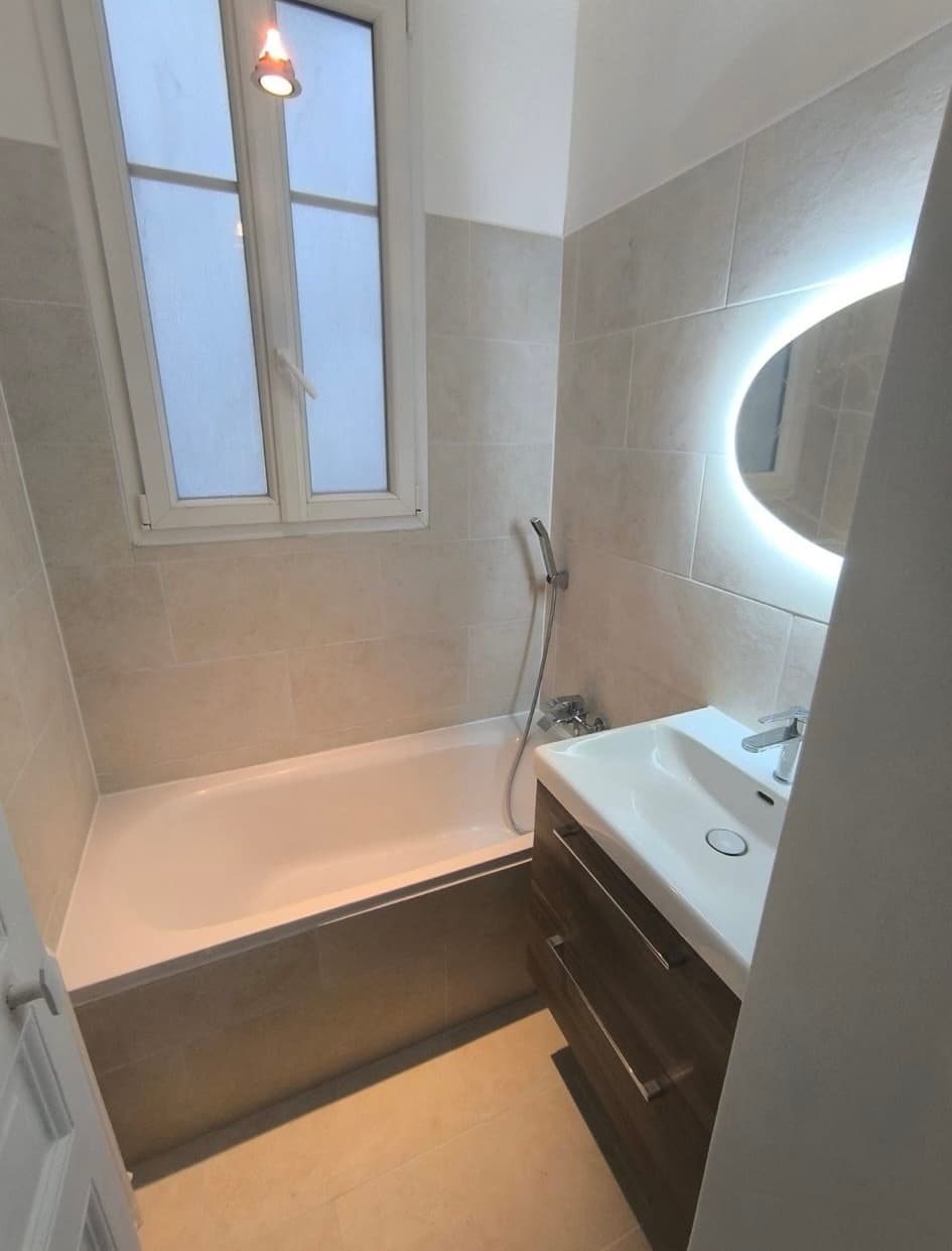 Salle de bain finie avec baignoire blanche et miroir rond rétro-éclairé
