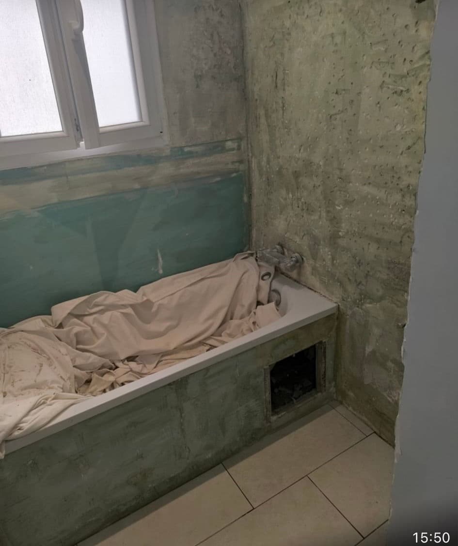 Salle de bain en cours de rénovation, murs verts, baignoire bâchée